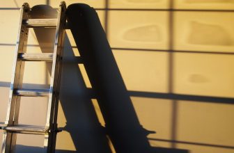 black metal ladder leaning on white wall